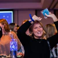 A grad smiles raising her hands holding a cookie